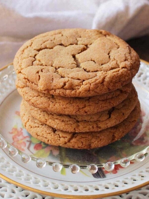 Four soft ginger cookies on a plate next to a white napkin