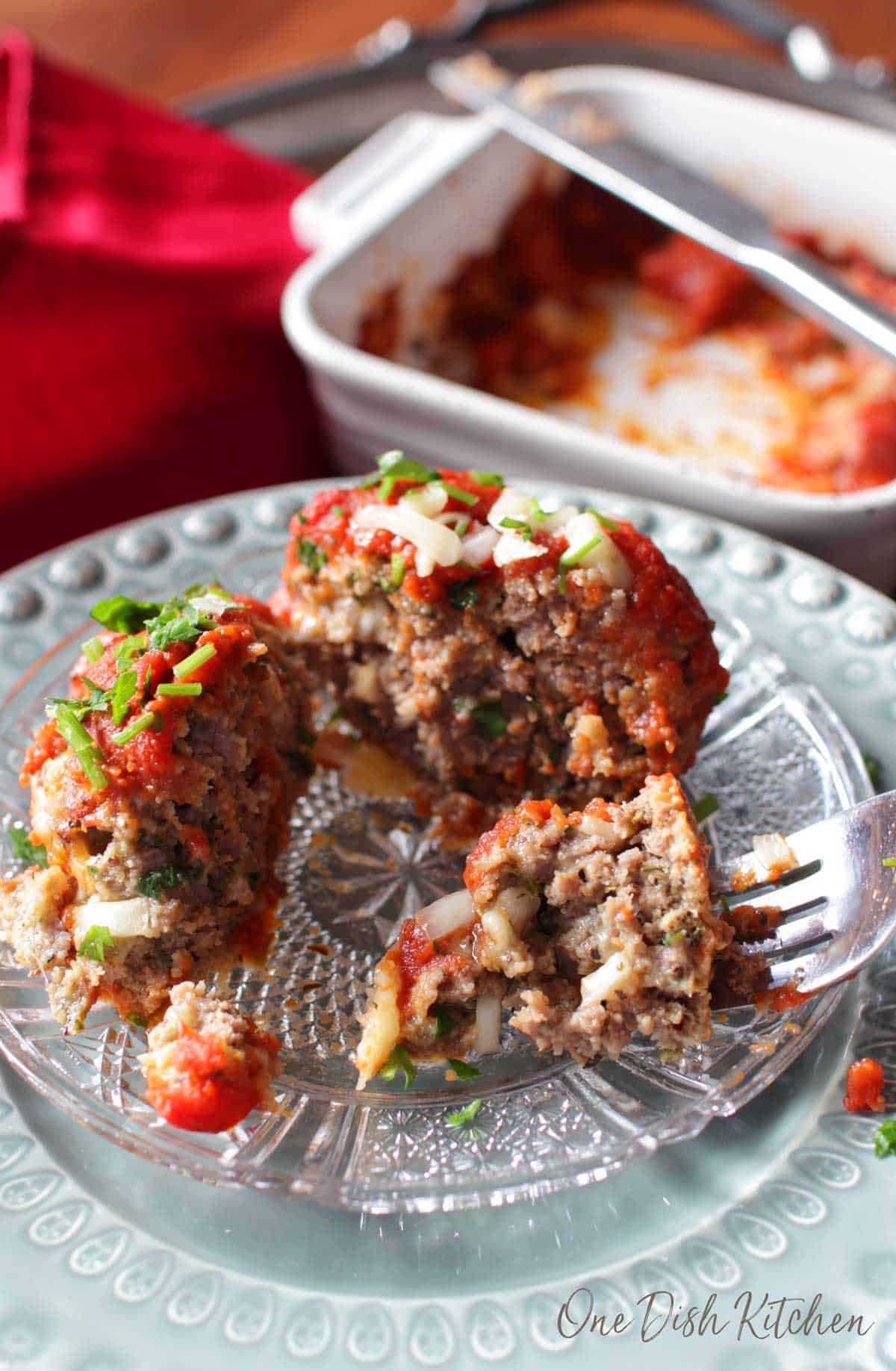 A forkful of meatball topped with tomato sauce and melted parmesan cheese. 