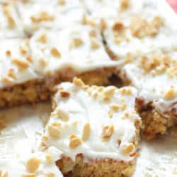 a pineapple cake baked in a sheet pan topped with white frosting and chopped nuts.