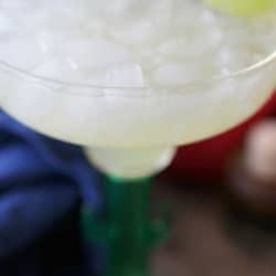 a margarita in a margarita glass with a lime wedge on the rim.
