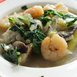 a bowl of soup with shrimp and spinach.