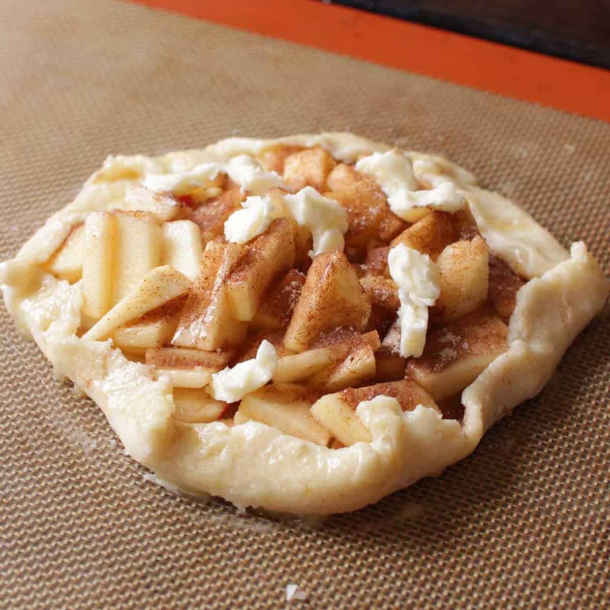 an unbaked apple galette on a small baking sheet.