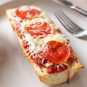 a french bread pizza on a white plate.