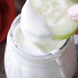 a slice of cucumber dipped into a jar of salad dressing.