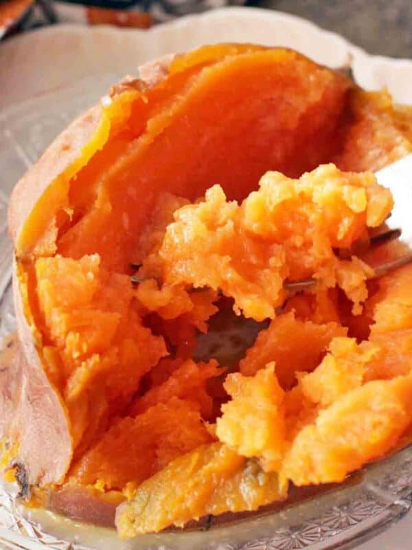 sweet potato that has been cut open with fork scooping out portion.