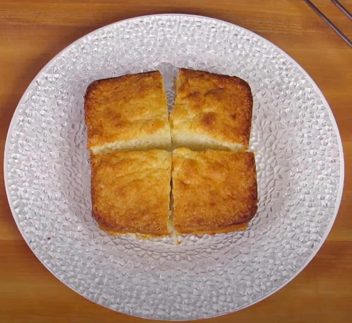 four small squares of pound cake on a white plate.
