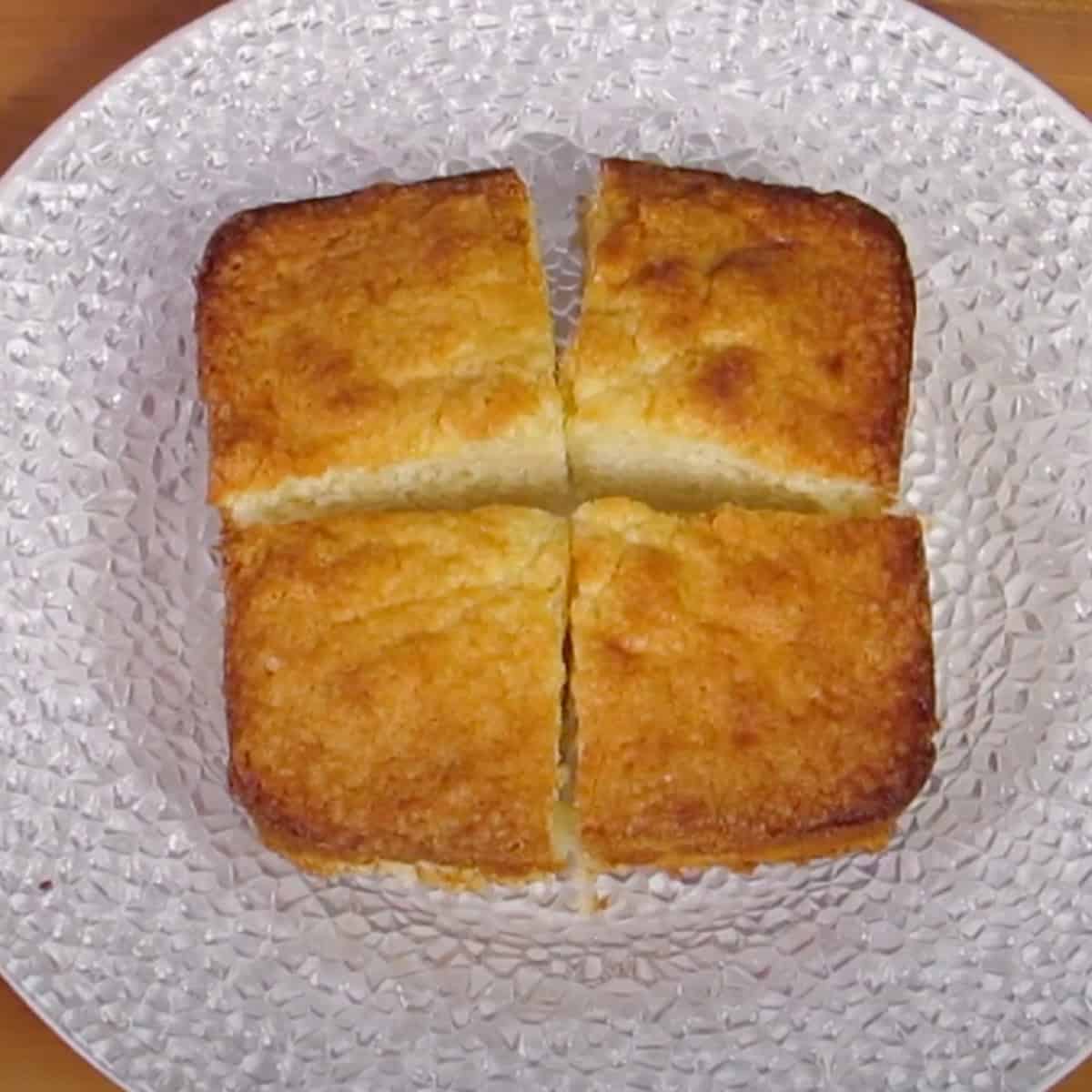 four small squares of pound cake on a white plate.