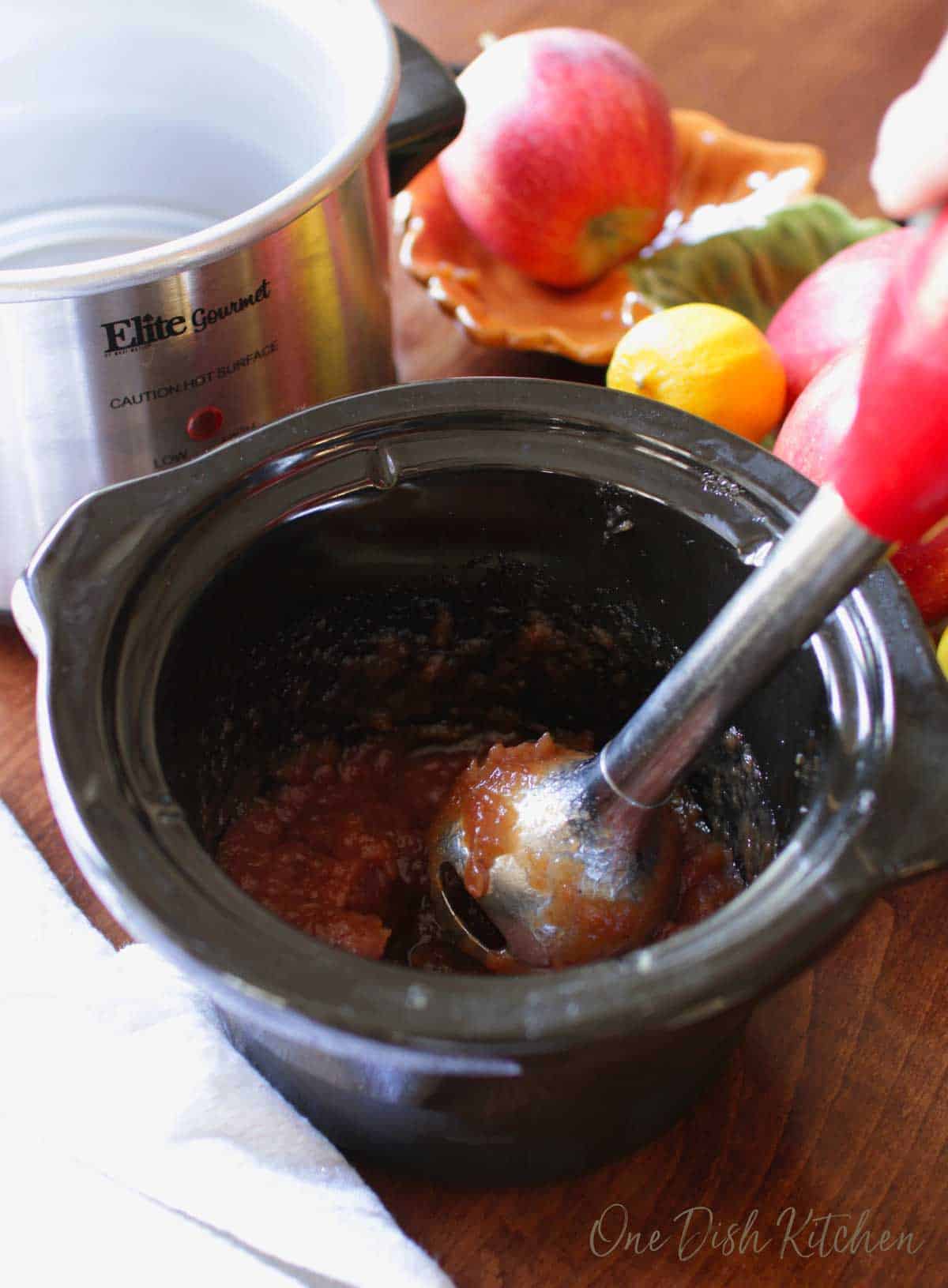 using an immersion blender to puree apple butter.