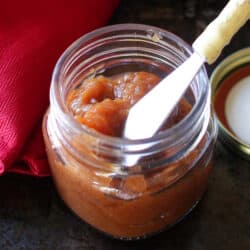 apple butter in a jar with a knife on the side.