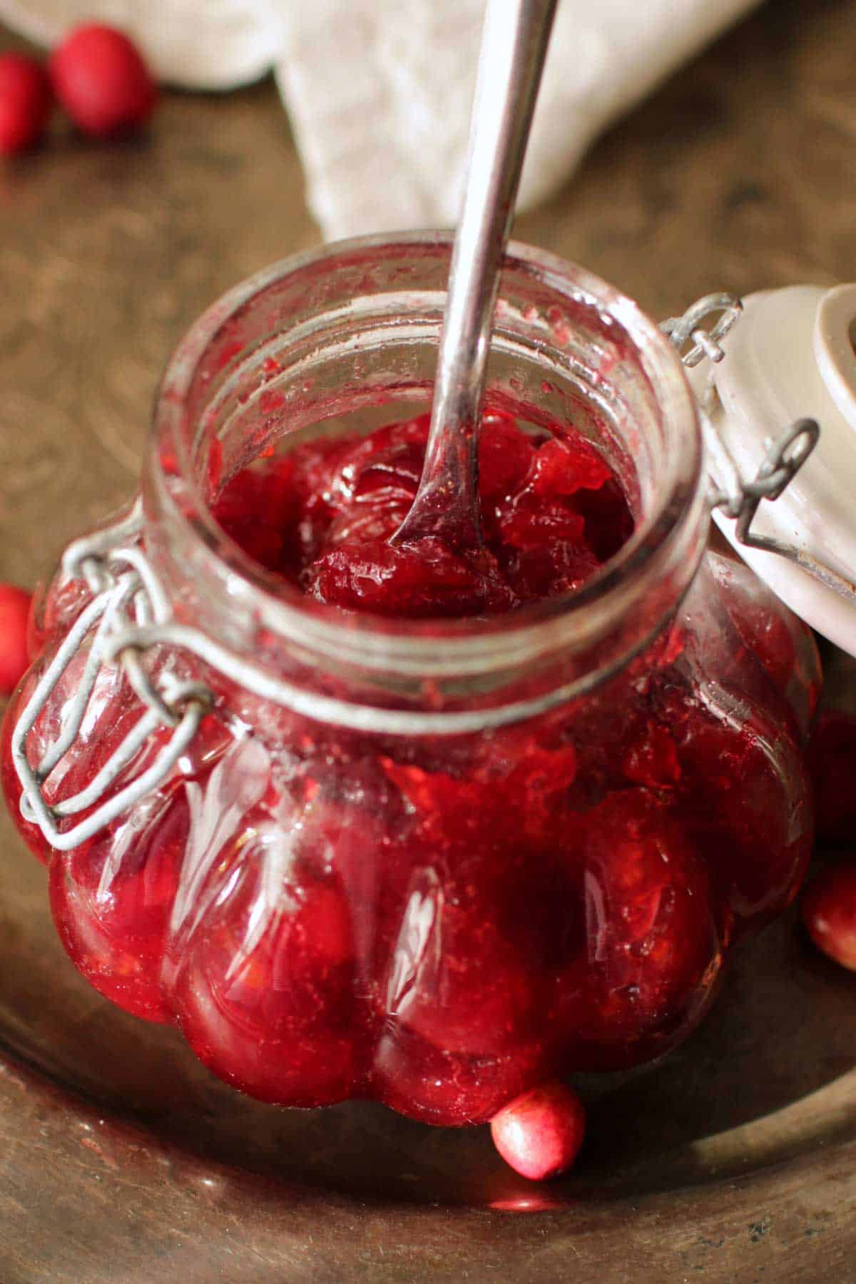 An closeup of a jar of cranberry jam with a spoon.
