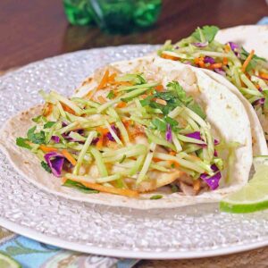 Fish Tacos on a glass plate with lime slices.