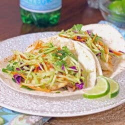 two fish tacos with broccoli slaw on a white plate.