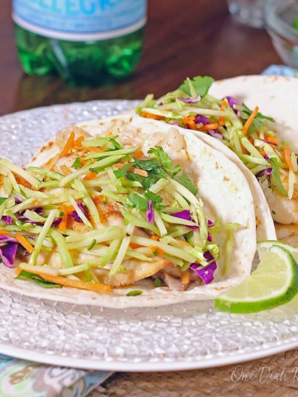 two fish tacos with broccoli slaw on a white plate.