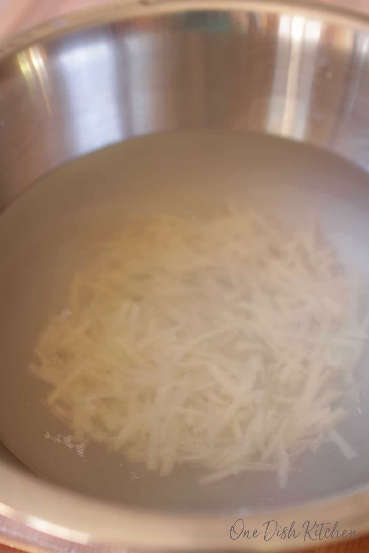 Raw potato shavings soaking in a big bowl of water.