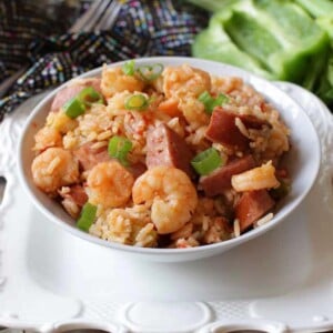 a bowl of shrimp and sausage jambalaya next to celery on a silver tray.