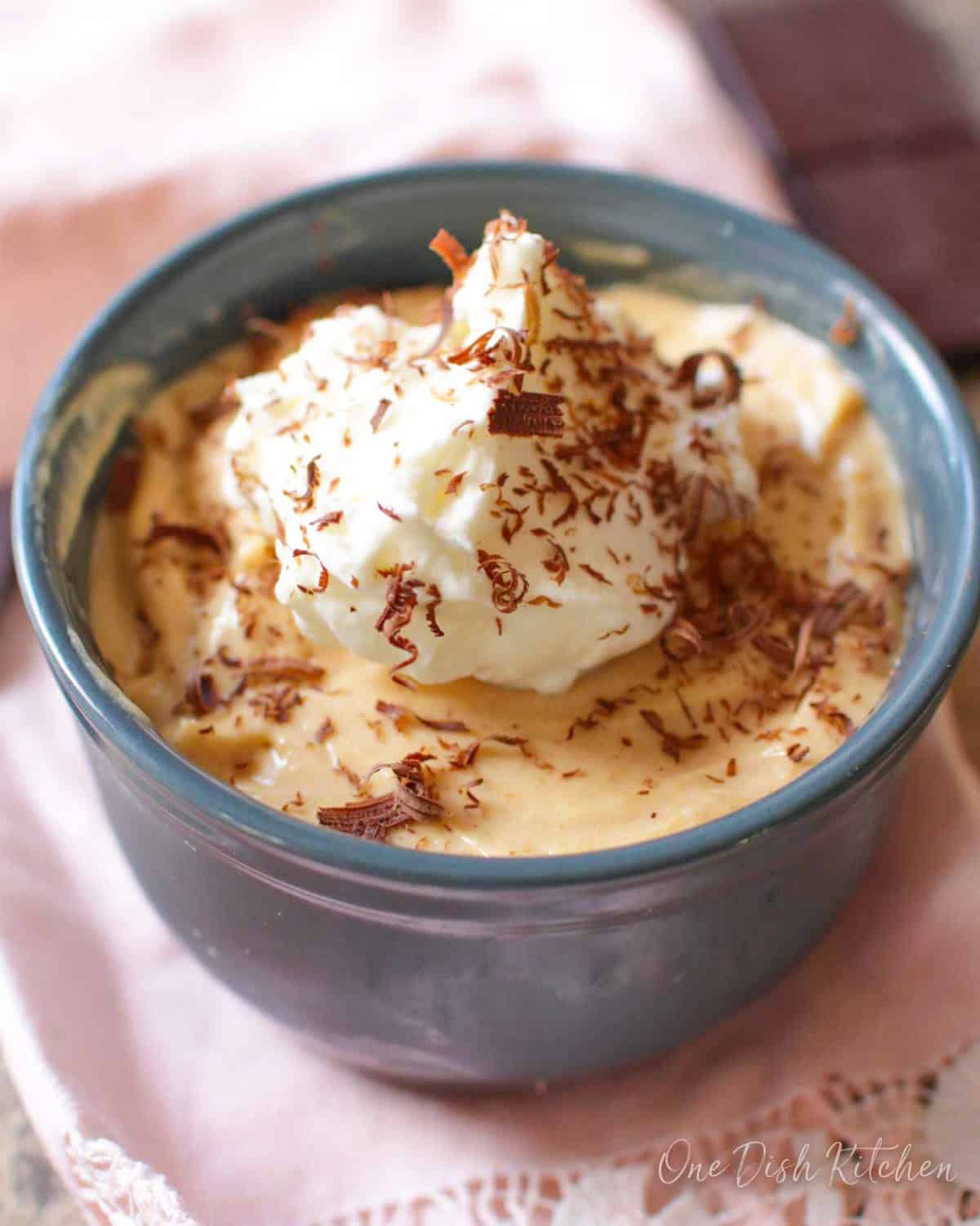 A small peanut butter pie in a blue bowl topped with whipped cream and chocolate shavings.