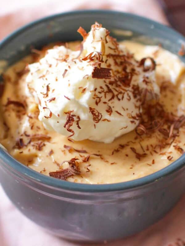 A small peanut butter pie in a blue bowl topped with whipped cream and chocolate shavings.