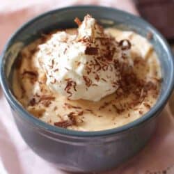 peanut butter pie in a green ramekin with whipped cream on top.