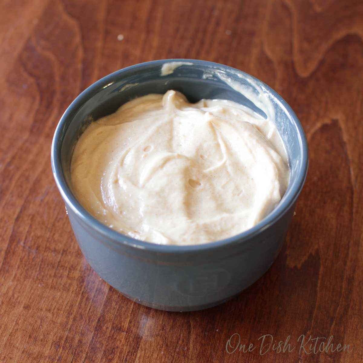 Peanut butter mixed with whipped cream in a blue ramekin on a wooden table.