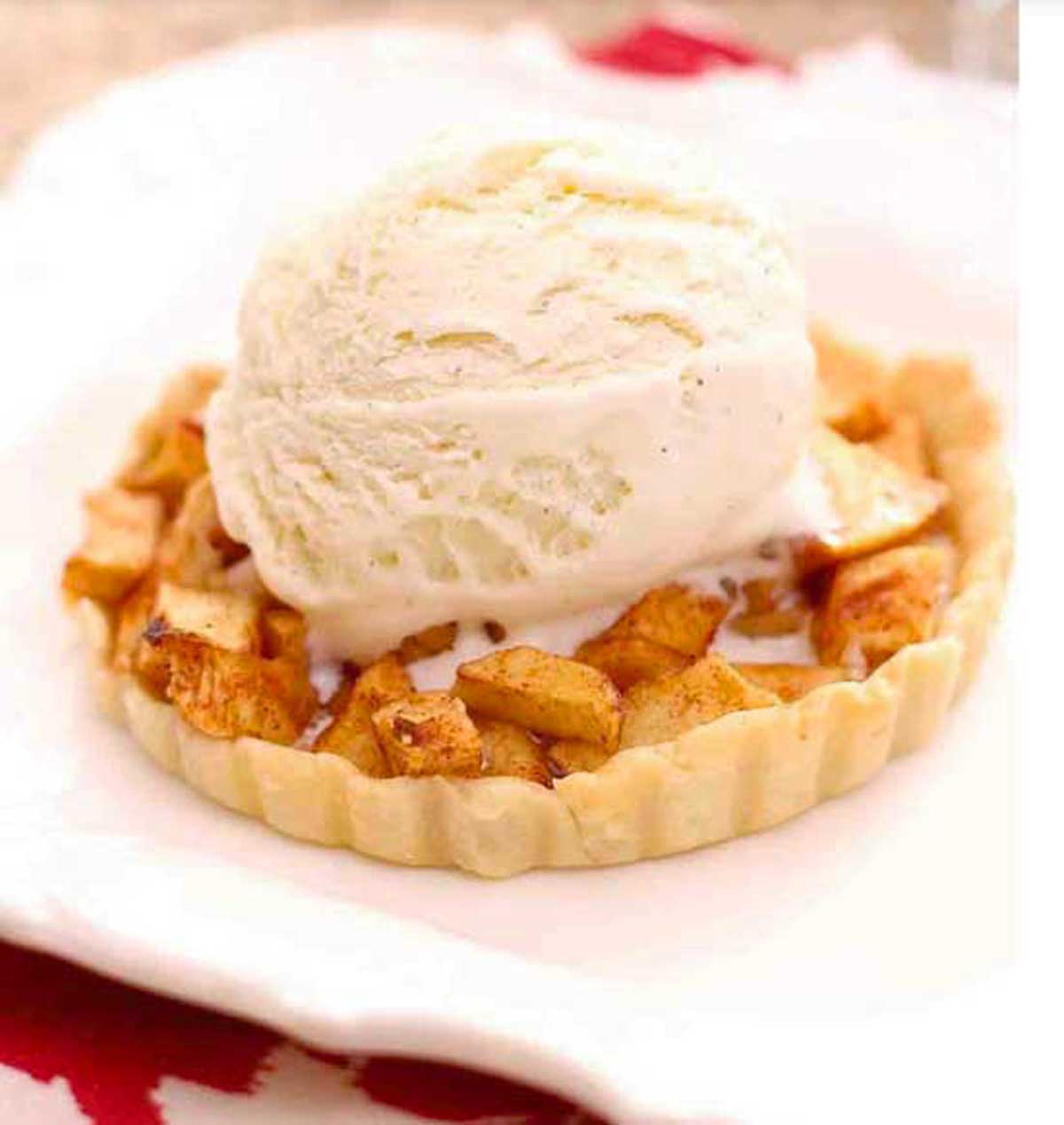 A mini apple pie made with a single serving pie crust recipe topped with a scoop of vanilla ice cream.
