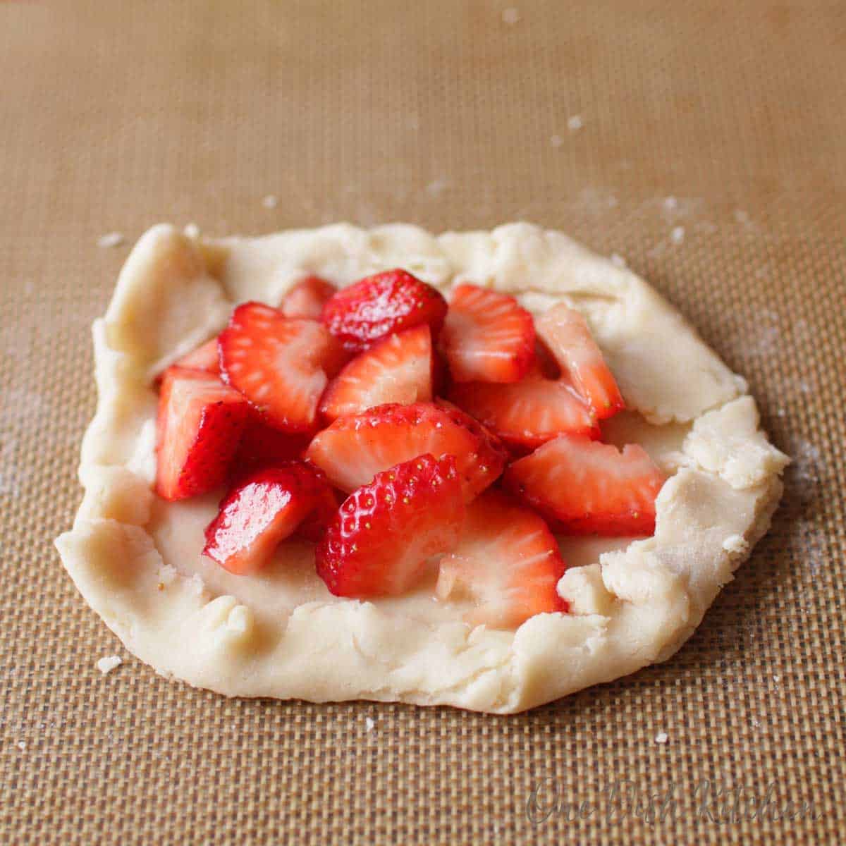 Small uncooked pie crust topped with fresh sliced strawberries.