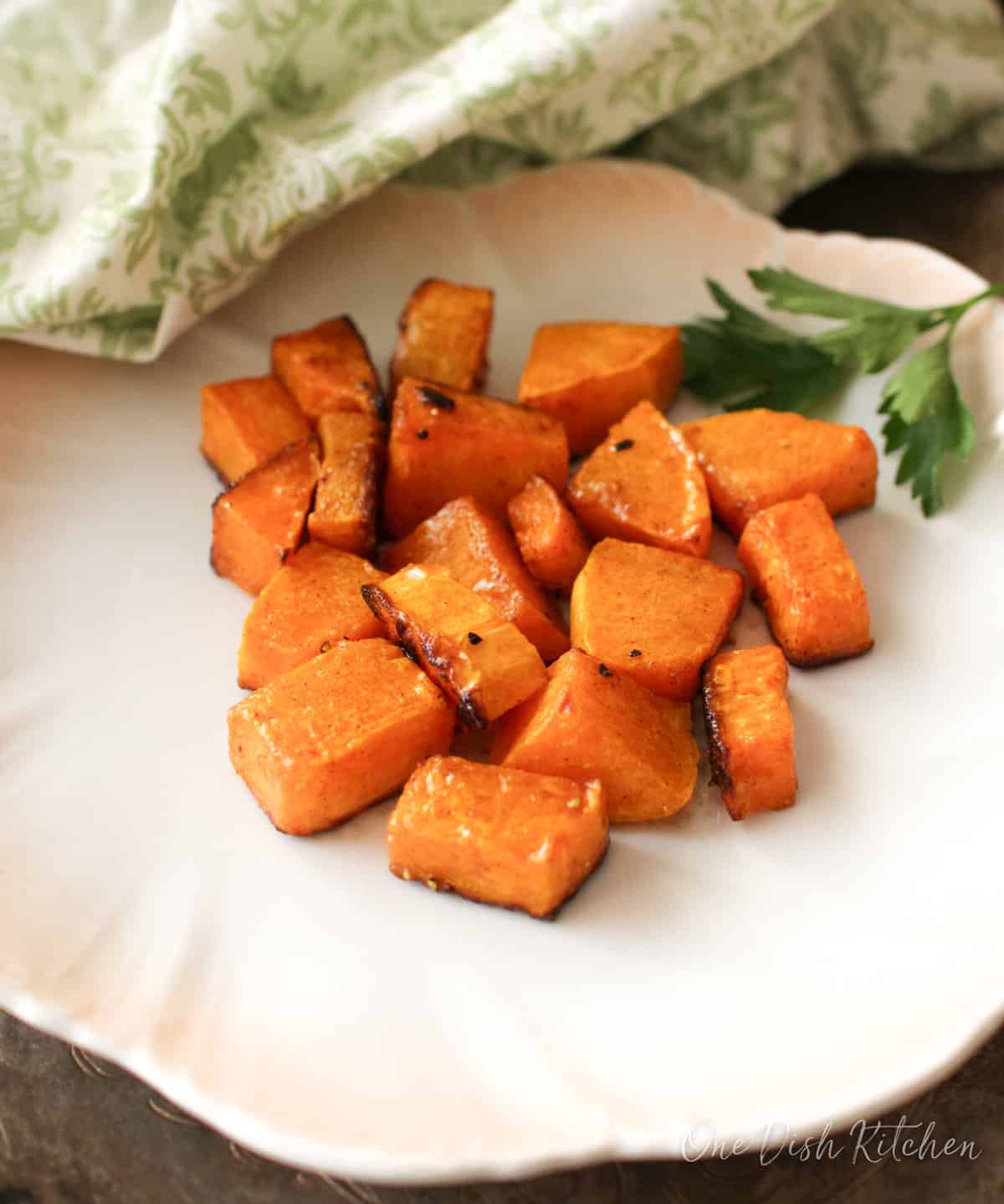 a white plate next to roasted butternut squash.
