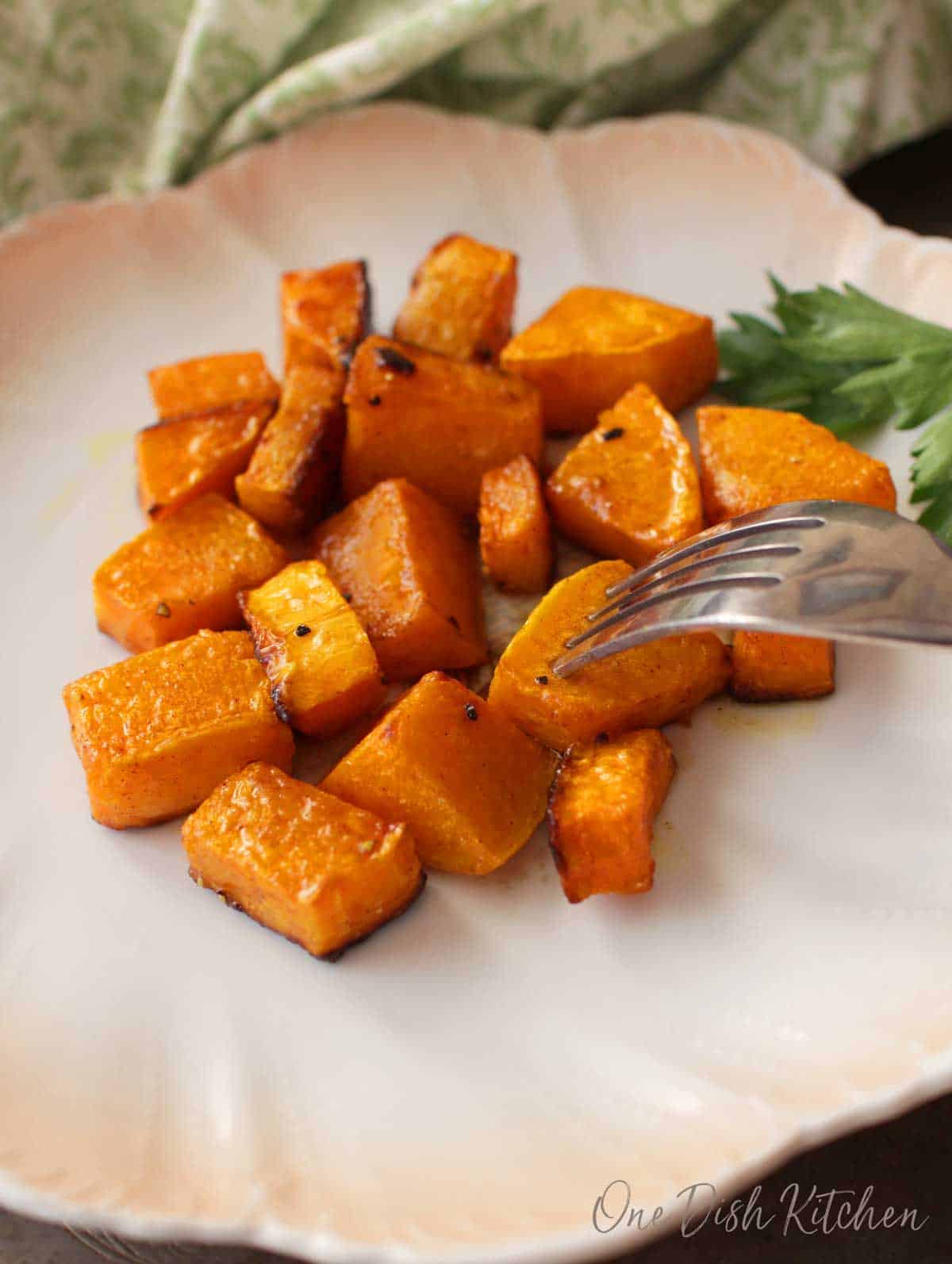 A fork diving into a plate of roasted butternut squash