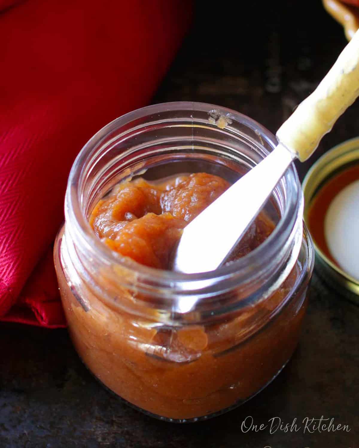 a small batch of apple butter in a jar with a knife on the side.