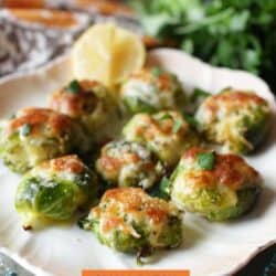 Nine crispy brussels sprouts topped with melted cheese on a white plate.