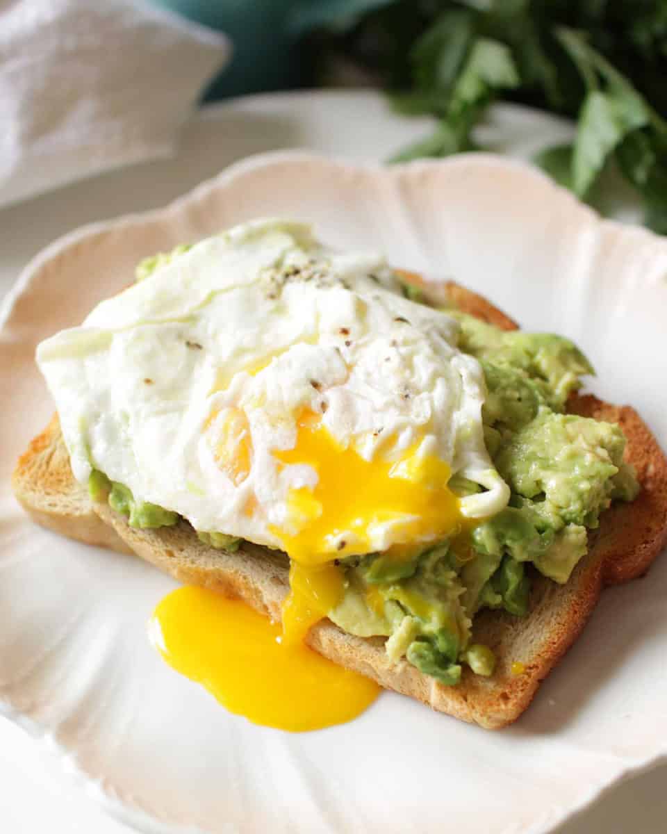 Avocado toast with a runny egg on top on a plate.