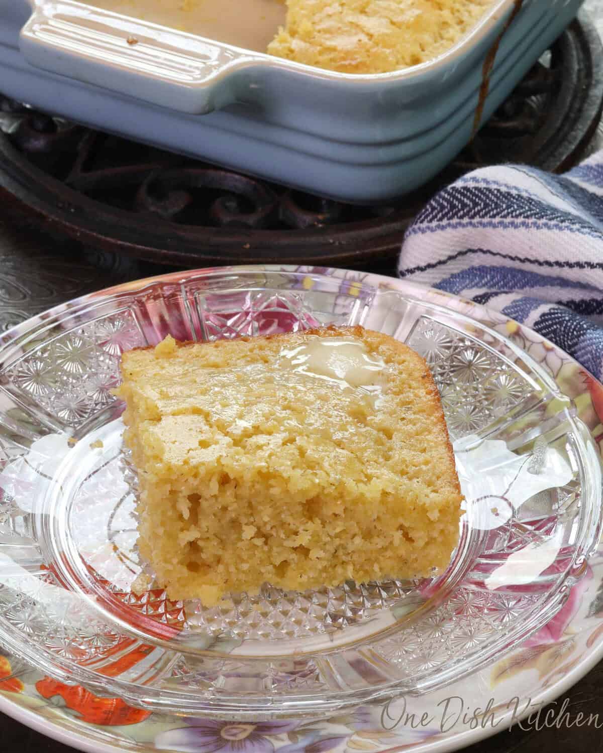 a small batch of cornbread in a baking dish with a slice of cornbread on a plate in front of it.