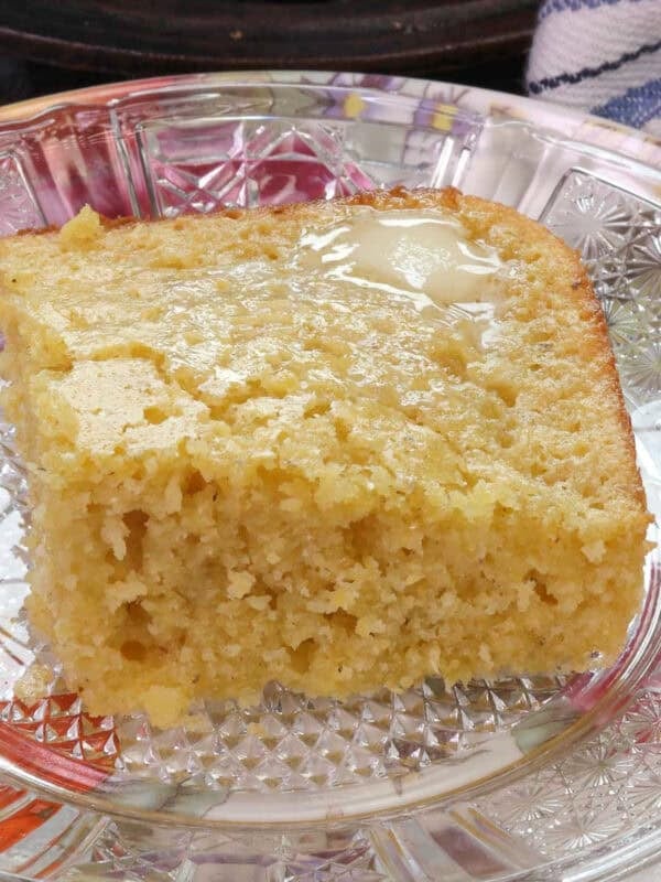 a small batch of cornbread in a baking dish with a slice of cornbread on a plate in front of it.