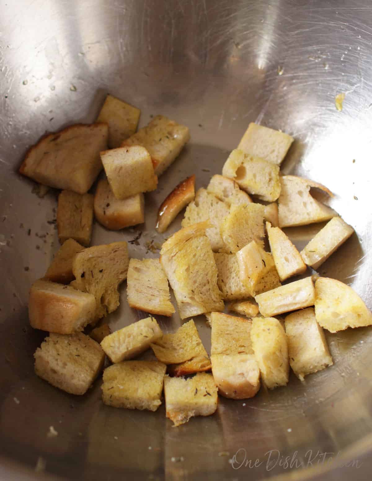 Croutons in a bowl topped with olive oil, salt, and herbs