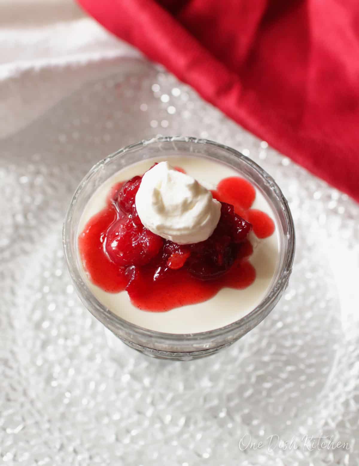a panna cotta in a dessert glass next to a red napkin.