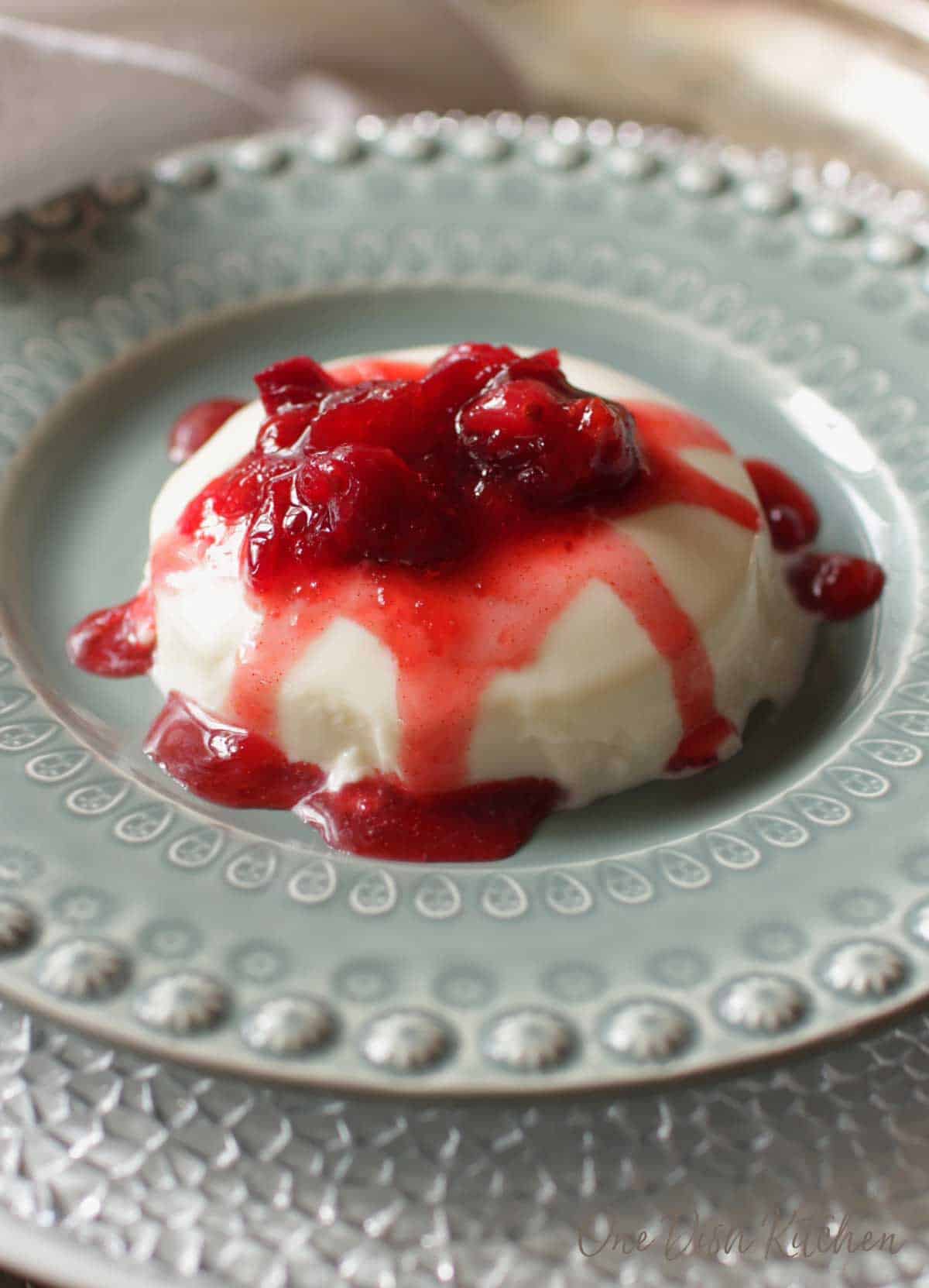 Panna cotta topped with cranberry jam on a plate