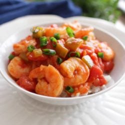 a white bowl filled with shrimp creole next to a blue napkin