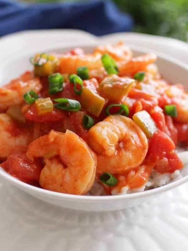 a white bowl filled with shrimp creole next to a blue napkin