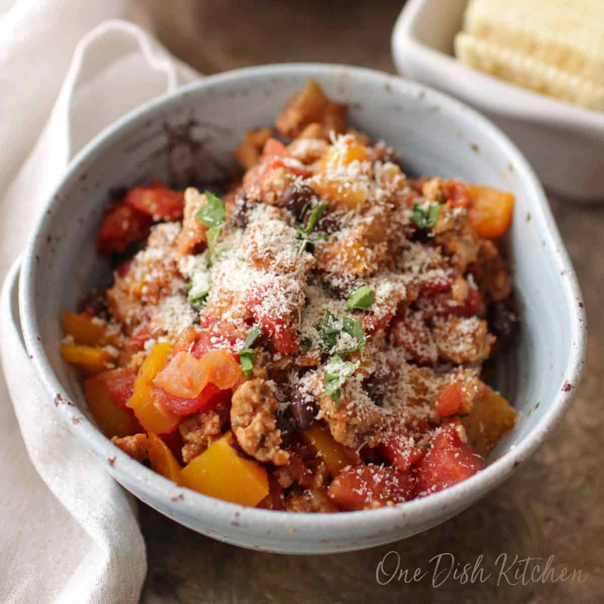 a single serving of ground turkey chili in a bowl topped with cheese.