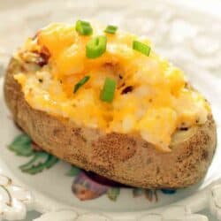 half of a baked potato with melted cheese and chives on top.