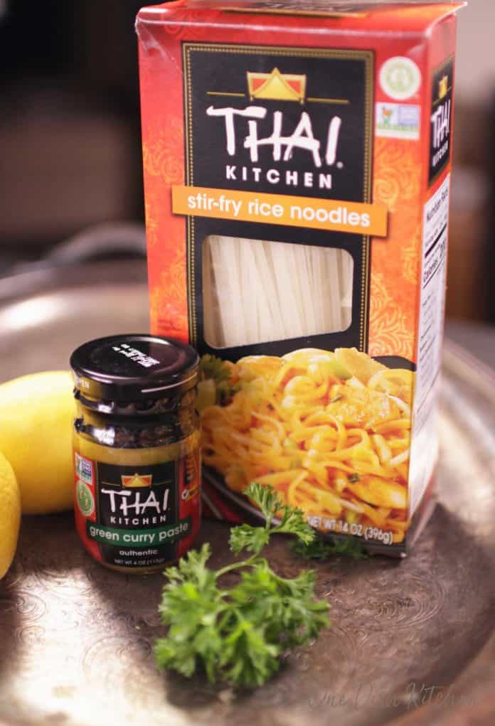 A small jar of Thai green curry paste and a box of rice noodles all on a metal tray.
