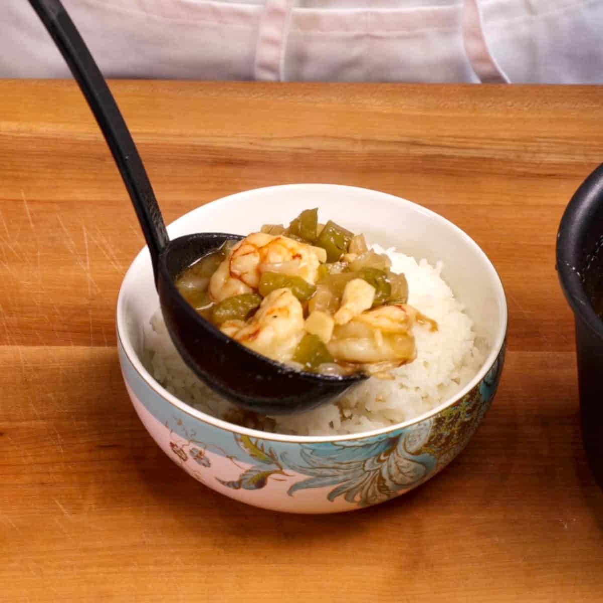 pouring gumbo over a bowl of rice