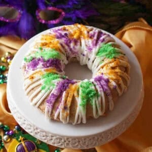 a king cake scone topped with glaze and colored sugar the colors of mardi gras.