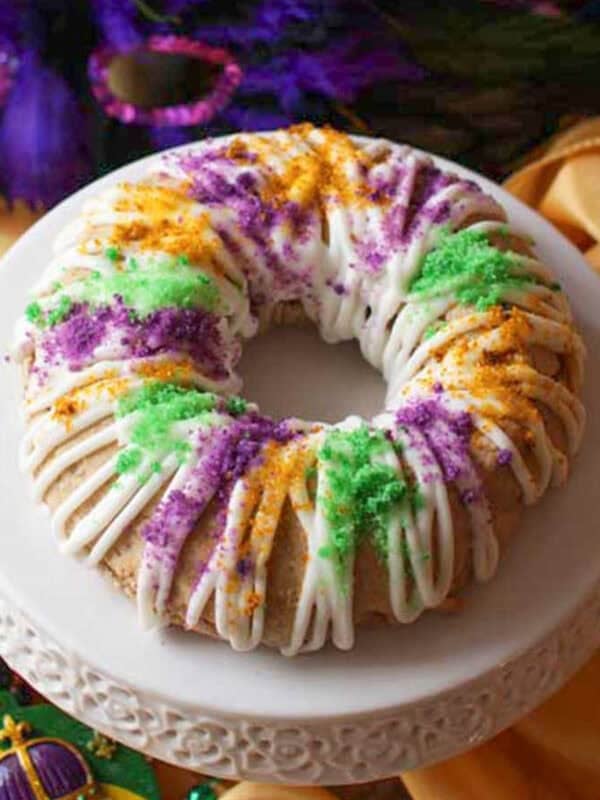 a king cake scone topped with glaze and colored sugar the colors of mardi gras.