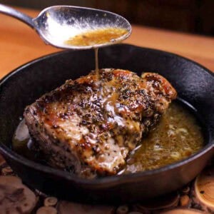 a small pork tenderloin in a cast iron skillet with butter sauce.