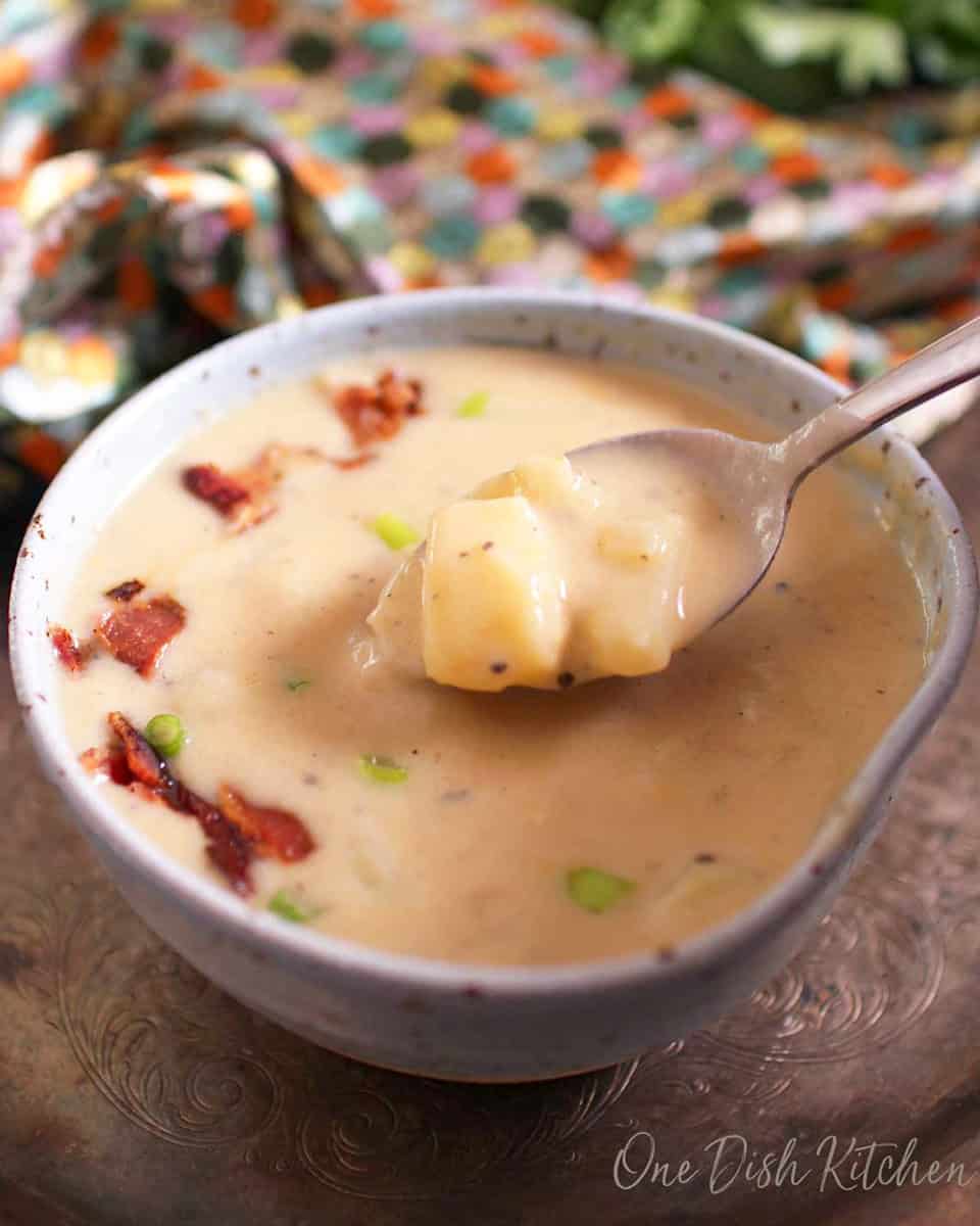 a bowl of potato soup with a spoon on the side.