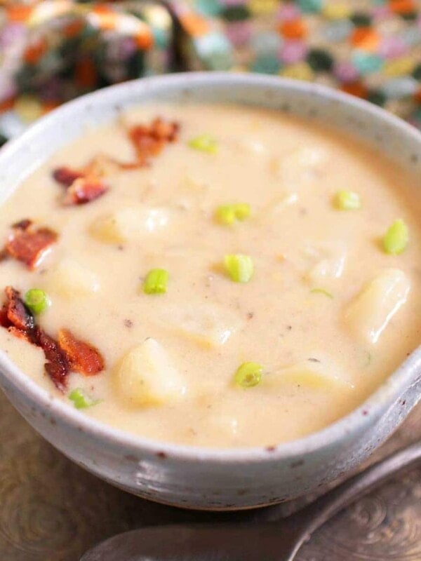 a blue bowl of potato soup with bacon on top