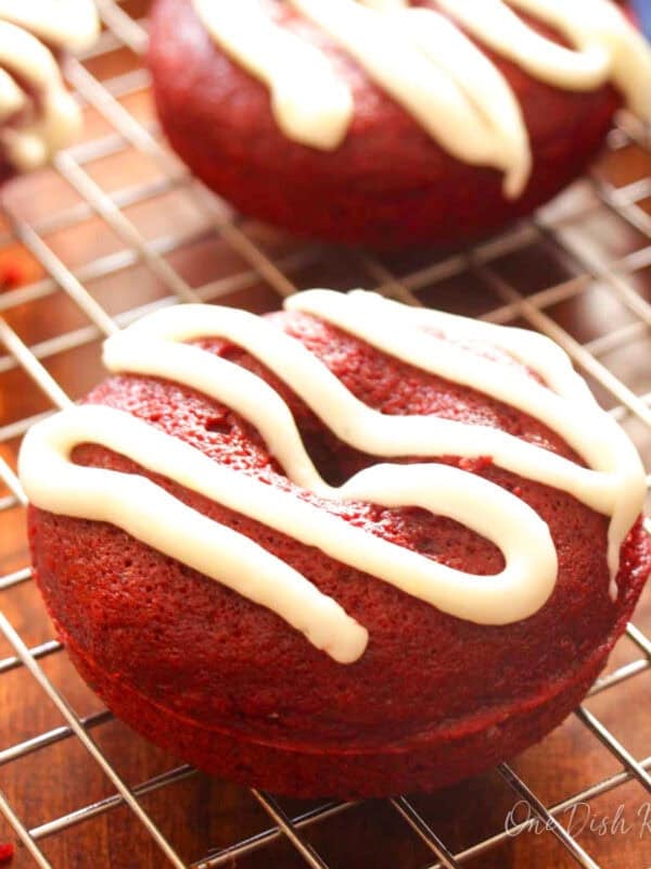 a small batch of baked red velvet donuts with cream cheese frosting on a cooling rack.