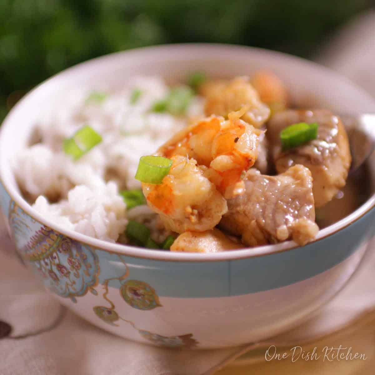 A closeup of a bowl of gumbo with shrimp, fish, and white rice.