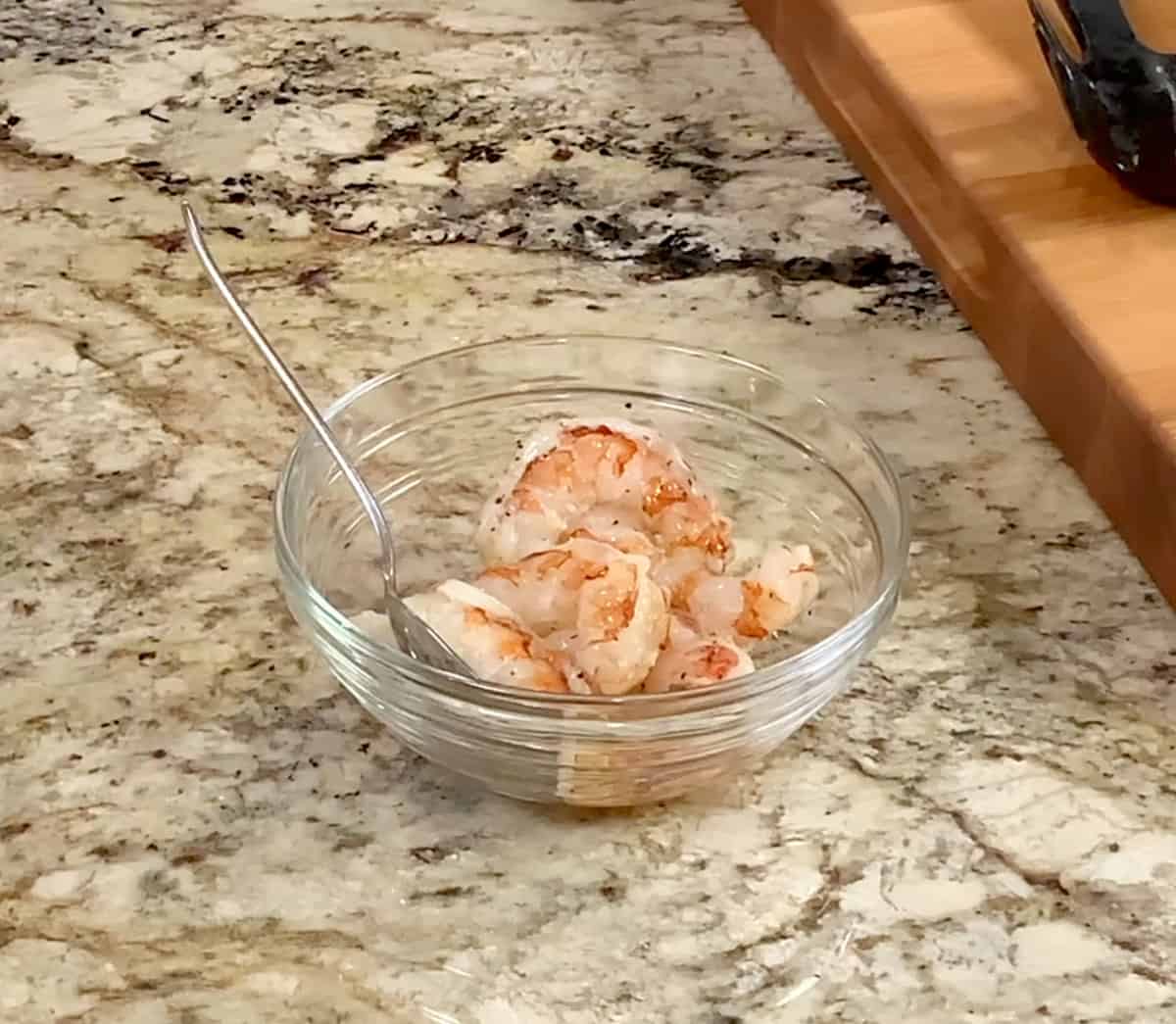 shrimp seasoned with salt and pepper in a small bowl on a kitchen counter