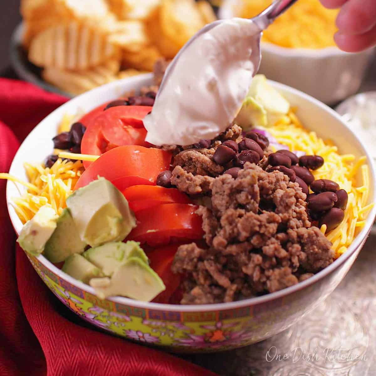 a taco salad topped with avocado and sour cream in a bowl.